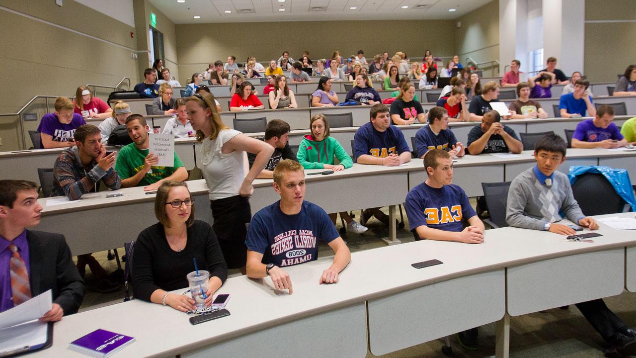 UE students prepare to listen to a lecture in an auditorium style classroom